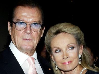 Roger Moore is looking at the camera while Kristina Tholstrup is distracted by something in the picture.